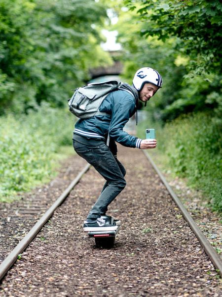 riding a onewheel gt on dirt trail with mobile app